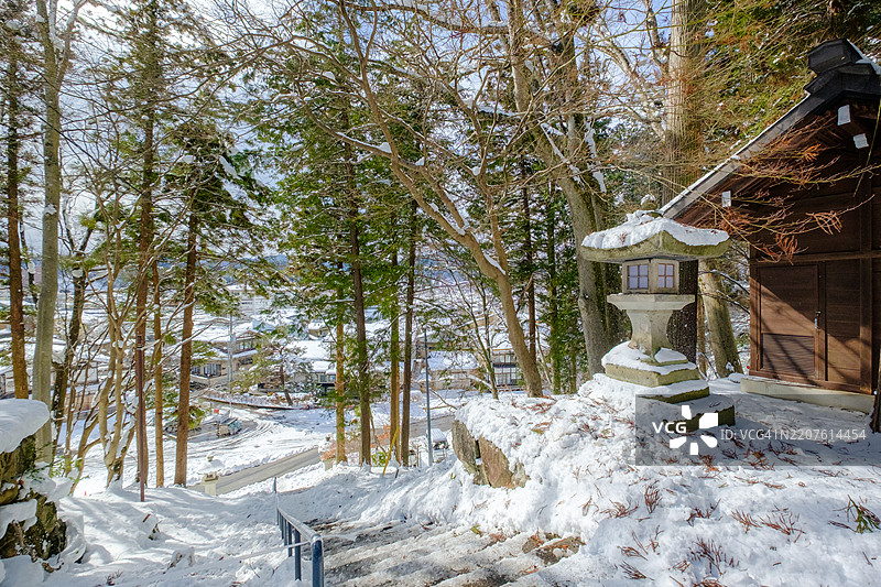 冬季高山城市背景下被雪覆盖的日本街灯。图片素材