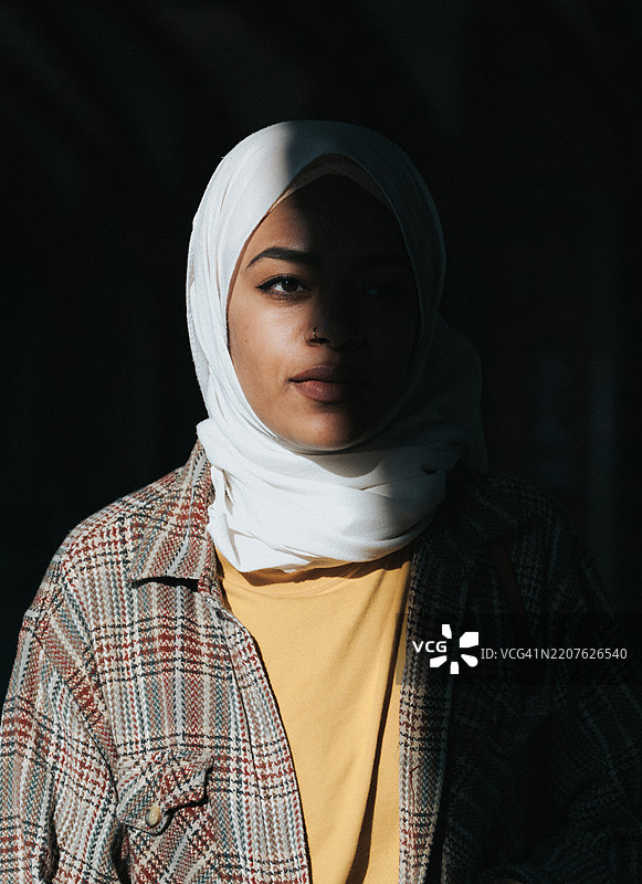 在阴影中，柏林一位年轻女性的肖像，头戴头巾。图片素材