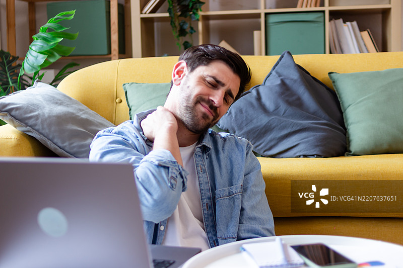 在家工作的男人感到颈部疼痛图片素材