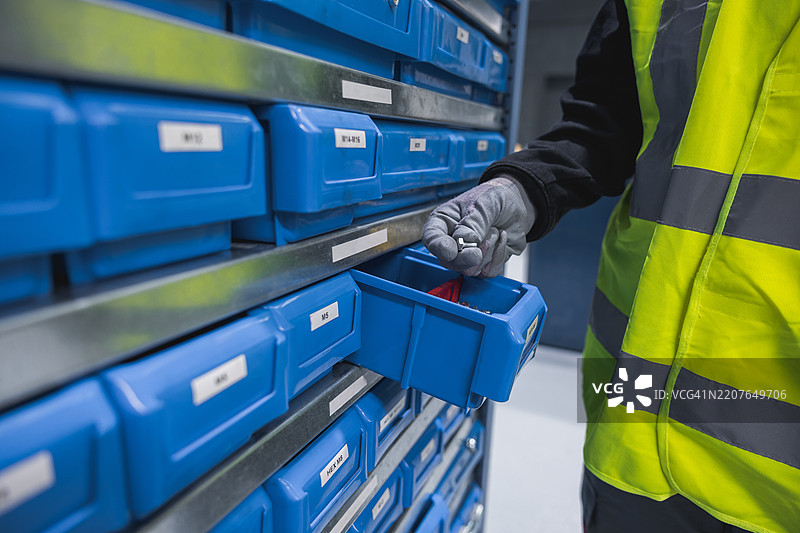 仓库工人在五金店的抽屉中挑选螺丝。图片素材