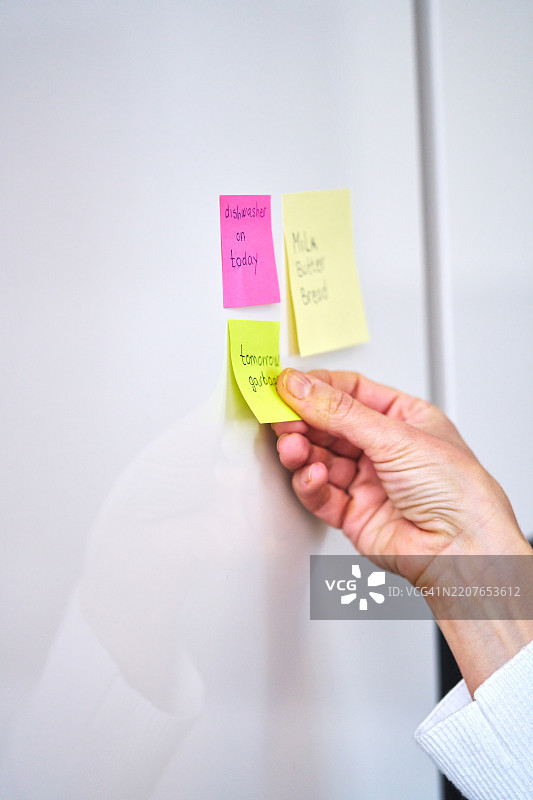 在冰箱上贴上购物清单的便利贴并整理家庭备忘录图片素材