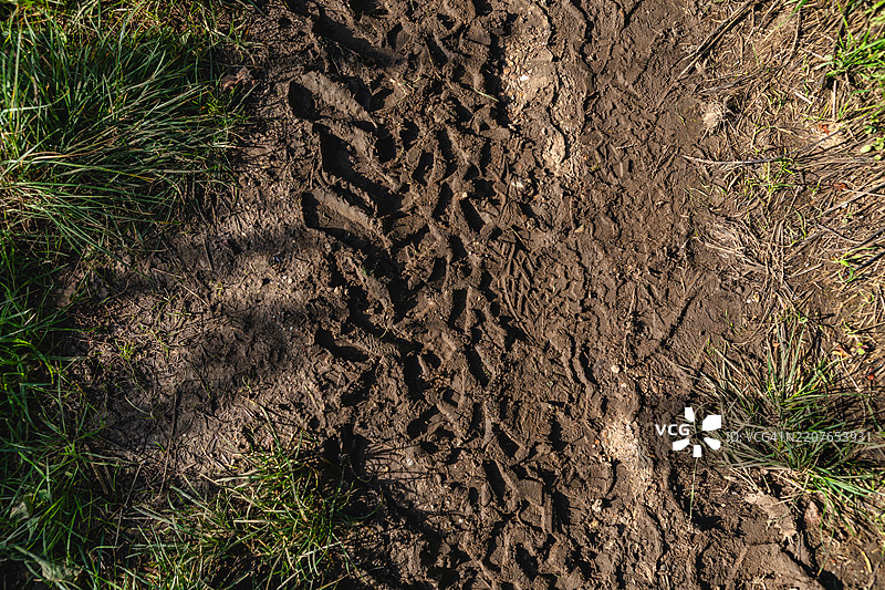 从上方俯视泥土中的车辆轮迹和脚印。图片素材