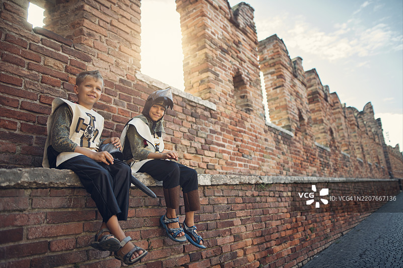 快乐的小城卫士坐在城墙上守卫城市。图片素材