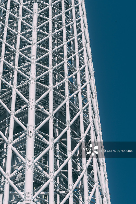 从下方仰望，东京晴空塔作为东京最具标志性的地标之一，雄伟地耸立在湛蓝的天空中。阳光照射在塔身上，使其顶端闪耀着璀璨的光芒。它位于日本东京的墨田区。图片素材