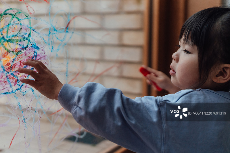 亚洲幼女在窗玻璃上画画图片素材