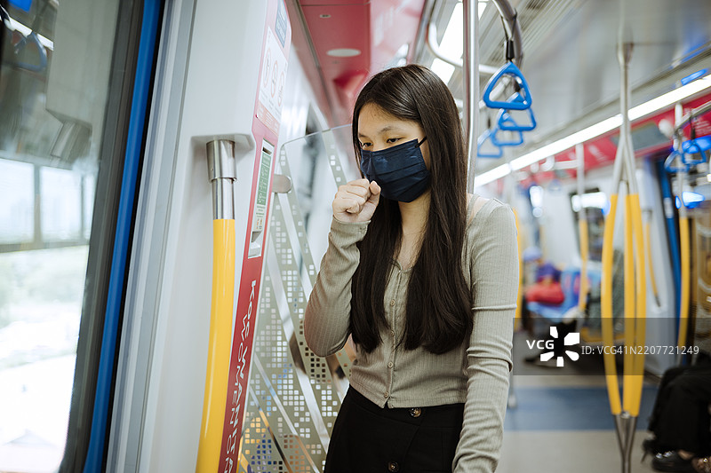戴着防护口罩的亚洲年轻女性在火车上。图片素材