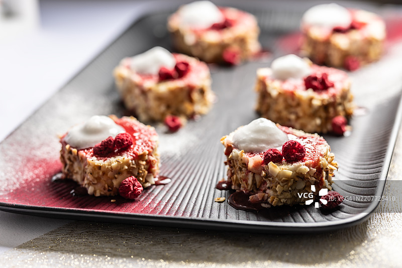 用黑色盘子装饰的杏仁卷，配有覆盆子和柠檬泡沫图片素材