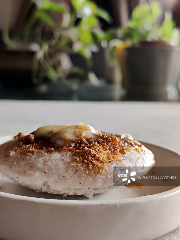 白色陶瓷盘中盛放的自制酥油浇头的Podi idli/辣椒粉idli特写/South Indian早餐图片素材