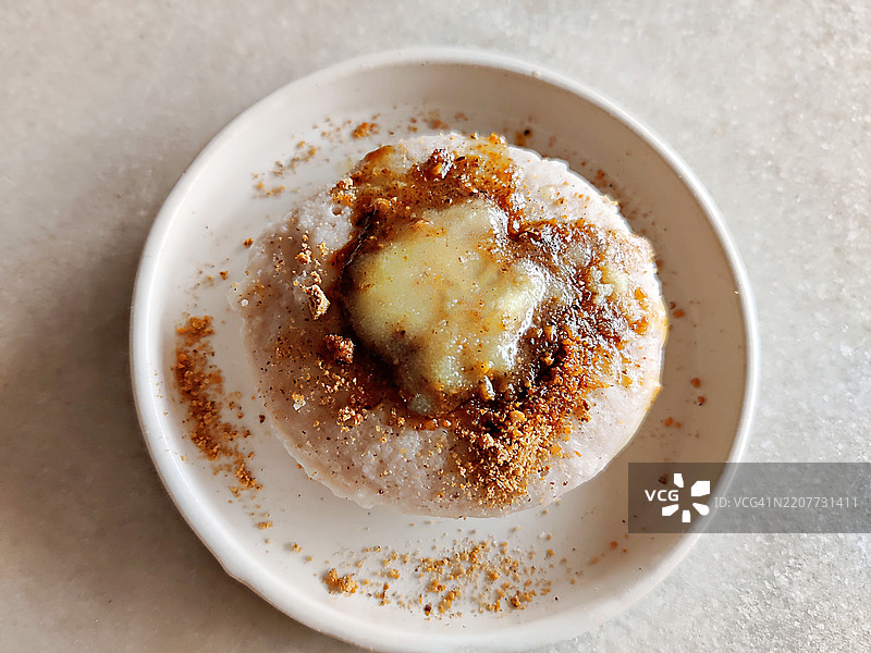 白色陶瓷盘中盛放的自制酥油浇在Podi idli/辣椒粉idli上的特写镜头/南印度早餐图片素材