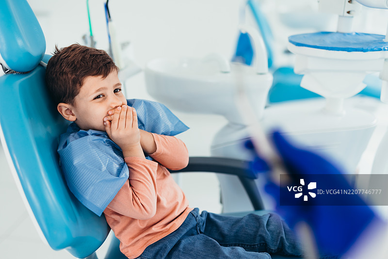 害怕的孩子用手捂住嘴巴在看牙医图片素材