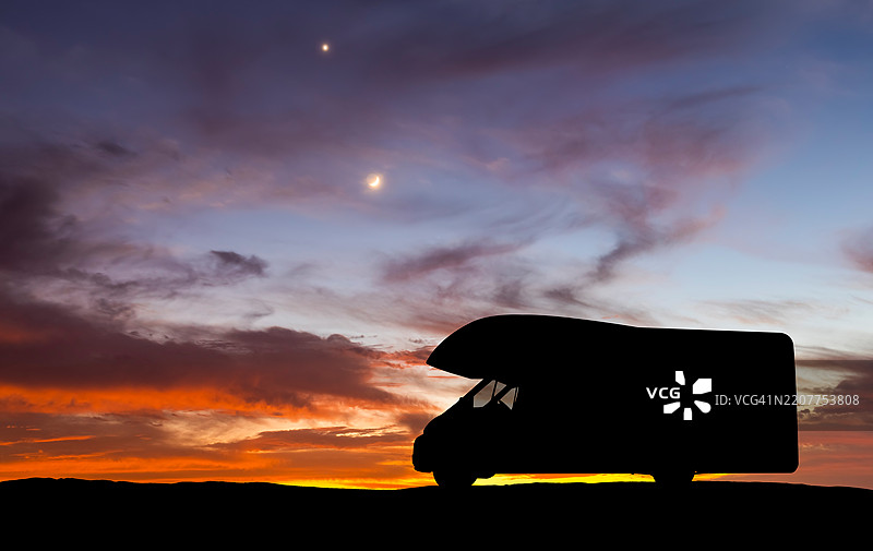 房车在美丽的日落天空下。公路旅行图片素材