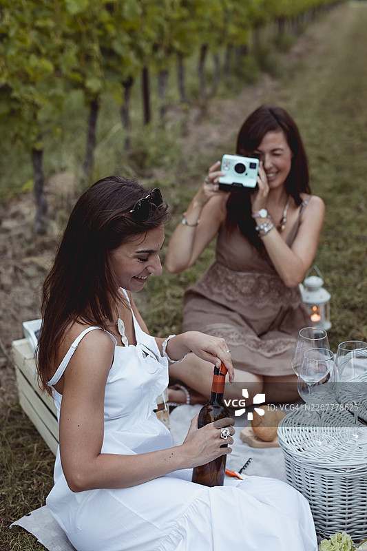 朋友们在葡萄园里野餐，一位女士用即时相机拍照图片素材