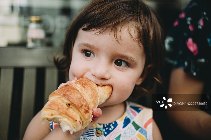 吃着可颂面包的小女孩肖像图片素材