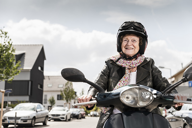 活跃的老年女士在城市中骑电动滑板车图片素材