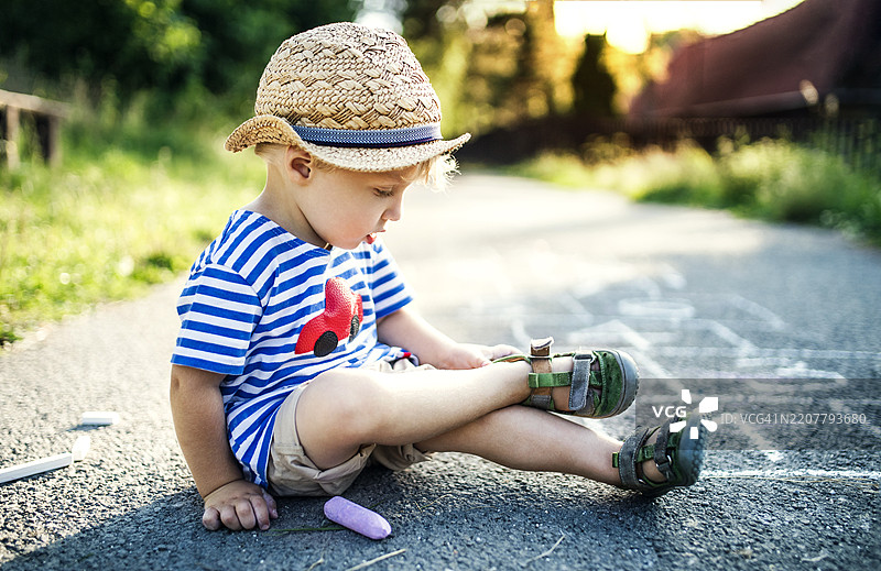 小男孩坐在街上脱鞋子图片素材