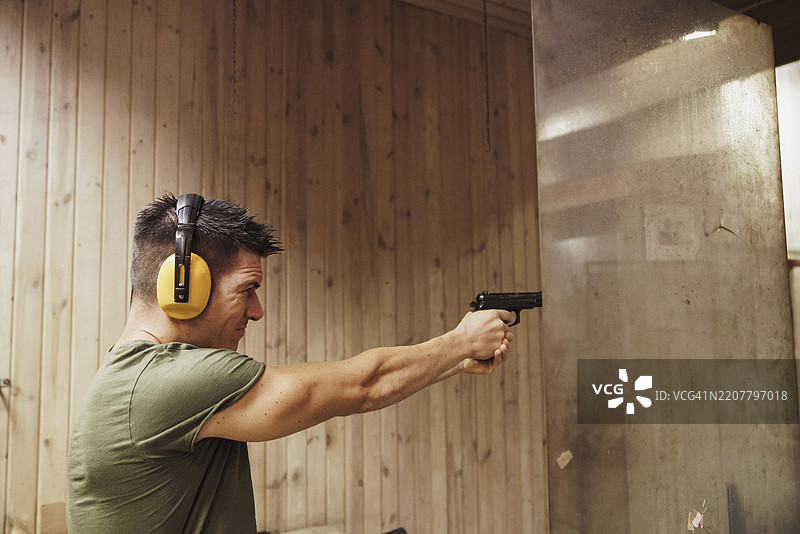 在室内射击场用手枪瞄准的男子图片素材
