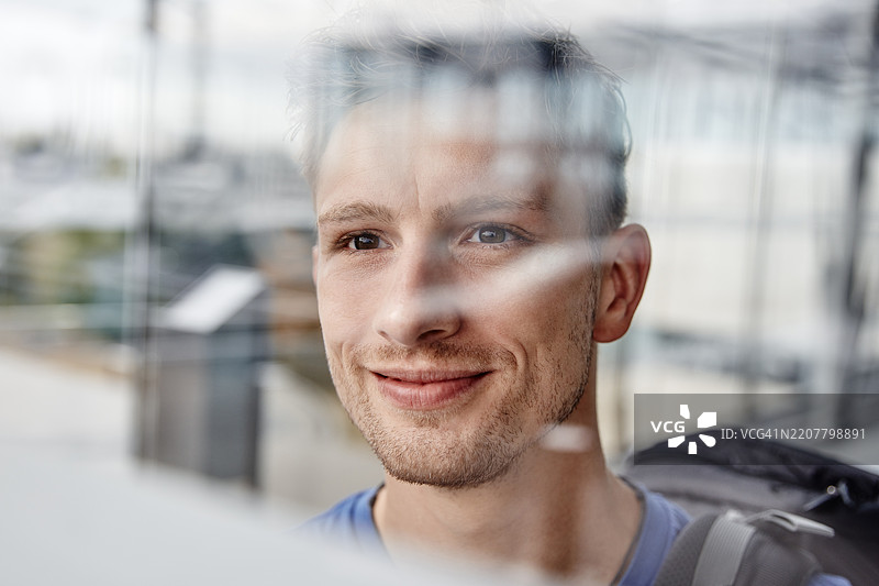 微笑的年轻男子望向窗外的肖像图片素材
