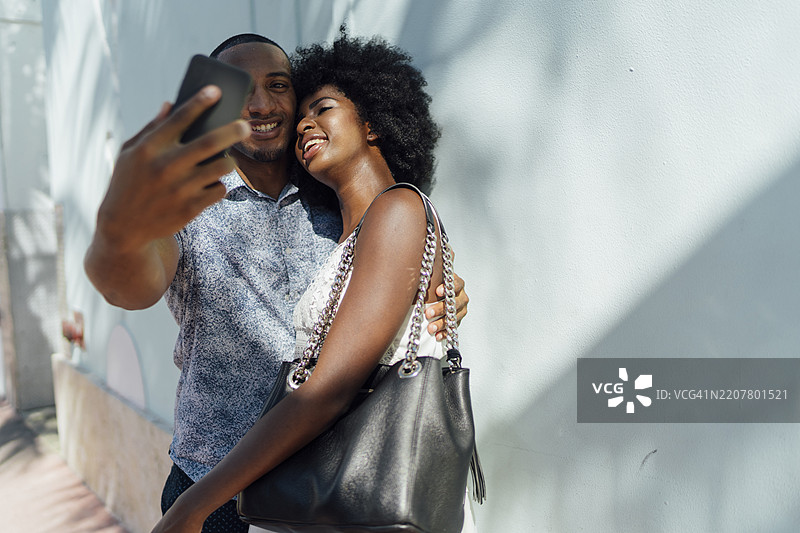 微笑的年轻情侣拥抱并自拍图片素材