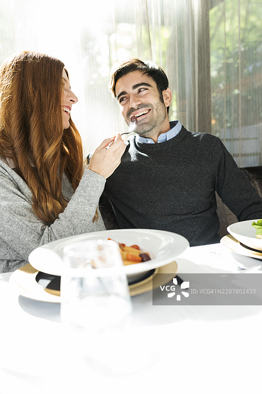 微笑的女人让男人在餐厅品尝食物图片素材