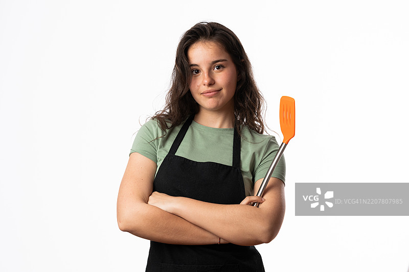 年轻厨师双臂交叉，手持铲子，直视镜头图片素材