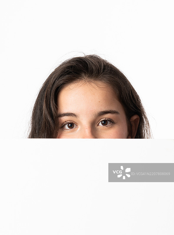 一个女孩躲在白色空白板后面图片素材