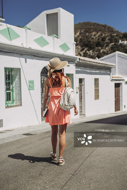 时尚年轻游客背影，背着背包在西班牙马拉加的弗里希利亚纳街道上行走图片素材