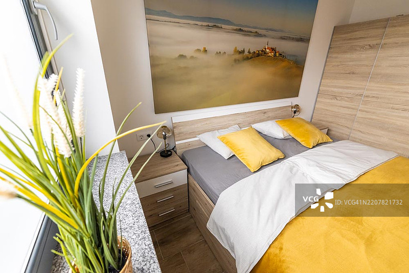 舒适的双人卧室，配有风景墙艺术和自然光线图片素材