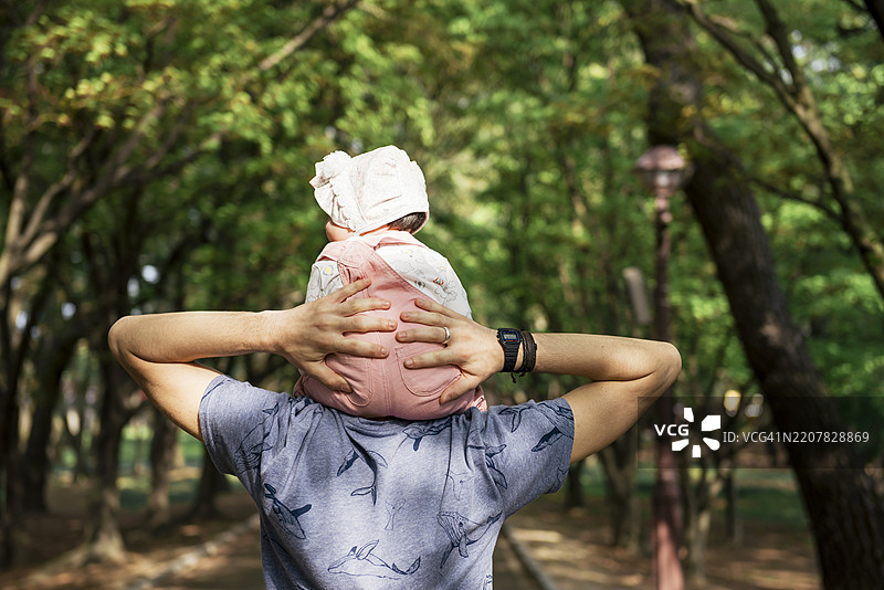 父亲在公园里背着女儿散步图片素材