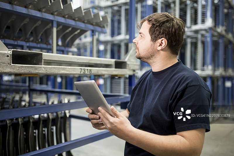 工人在工厂仓库使用平板电脑图片素材