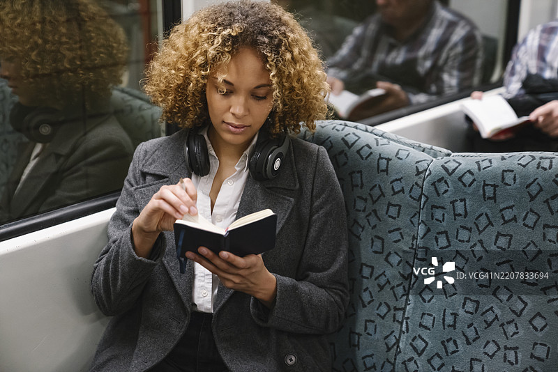 地铁上拿着笔记本的女性图片素材