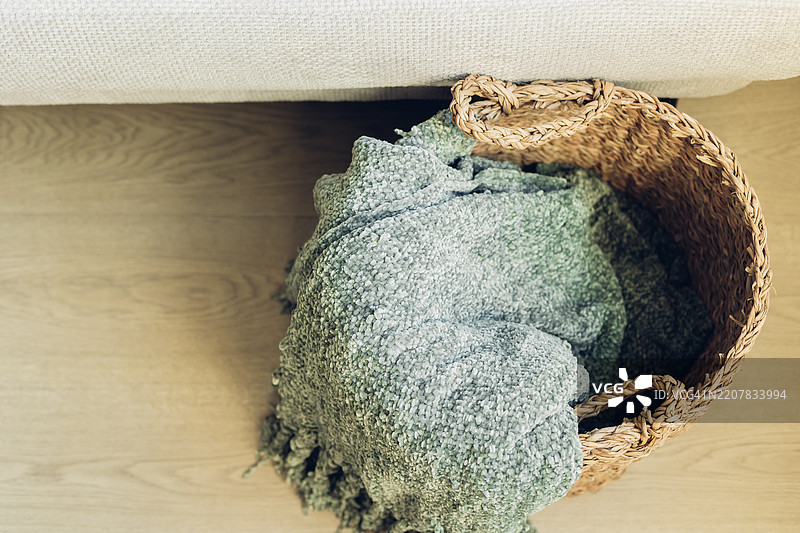 舒适房间里，靠近舒适沙发的编织篮子和柔软的毛毯图片素材