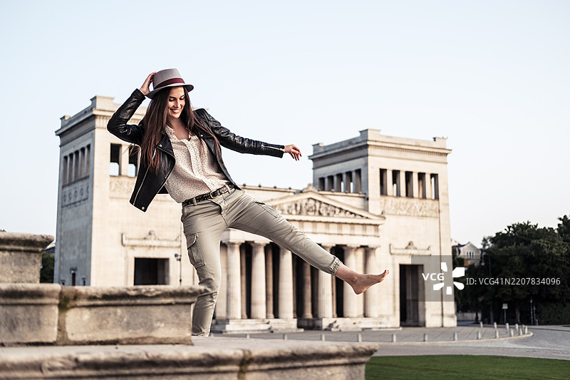快乐的年轻女性在德国慕尼黑的科宁斯广场的楼梯上跳舞图片素材