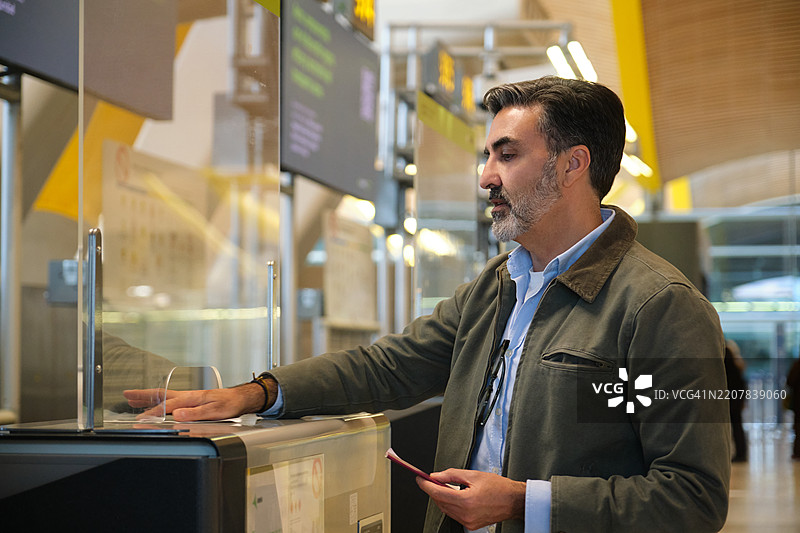 成熟男性在机场使用自助值机亭图片素材