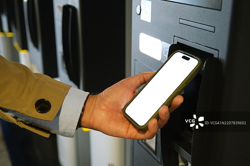 商人使用智能手机在自助结账机付款图片素材