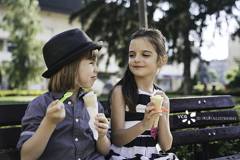 阳光明媚的公园里，顽皮的孩子们分享冰淇淋图片素材