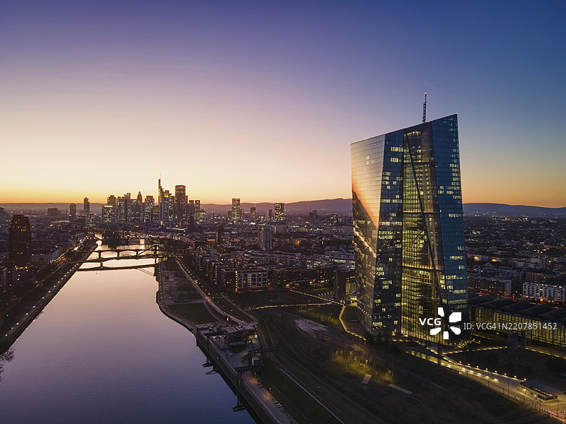 欧洲中央银行（ECB）办公室的灯光和法兰克福天际线在日落后的傍晚闪烁着光芒。（无人机航拍），法兰克福东港，德国黑森州法兰克福，欧洲图片素材