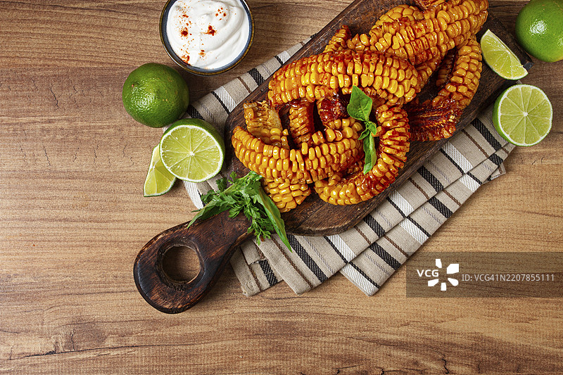 玉米肋骨，配奶油酱、香料和青柠，开胃菜，放在木砧板上，自制，无人。图片素材