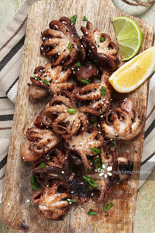 烤小章鱼，配青葱和柠檬角，放在木砧板上，自制，无人。图片素材