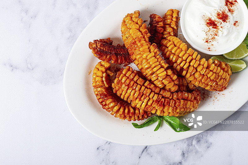 玉米肋骨，配奶油酱、香料和青柠，开胃菜，放在白色盘子上，自制，无人。图片素材