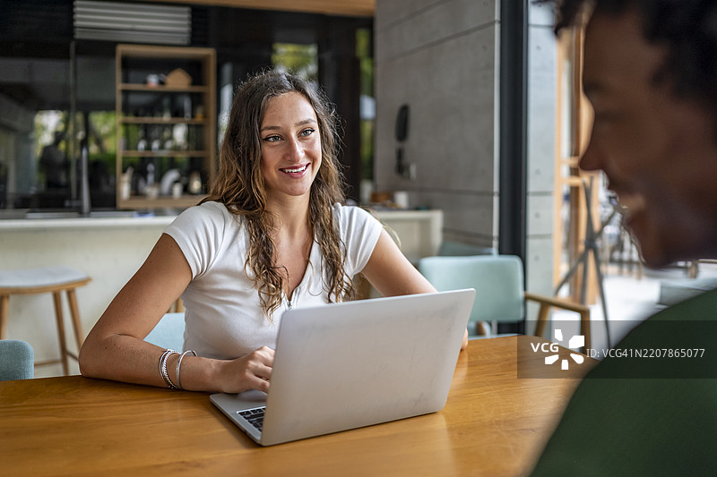 微笑的女性在现代舒适的工作空间中使用笔记本电脑图片素材