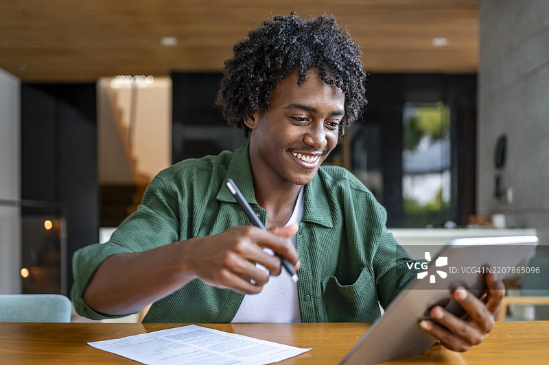 微笑的男子在木桌上使用平板电脑远程工作图片素材