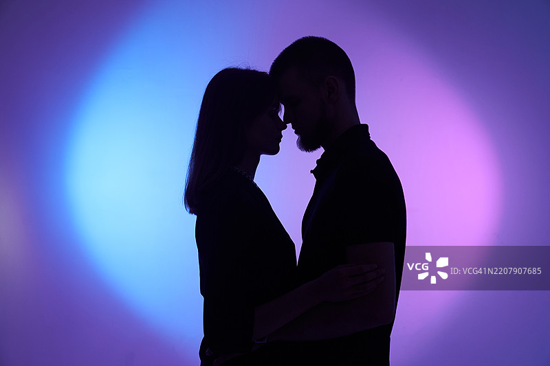 渐变背景上的剪影配对。两个人在紫色和蓝色的圆形背景上。图片素材