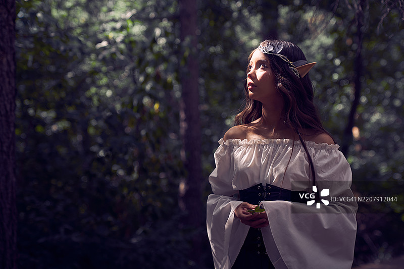 穿着服装的精灵女性站在森林中的大自然里。图片素材