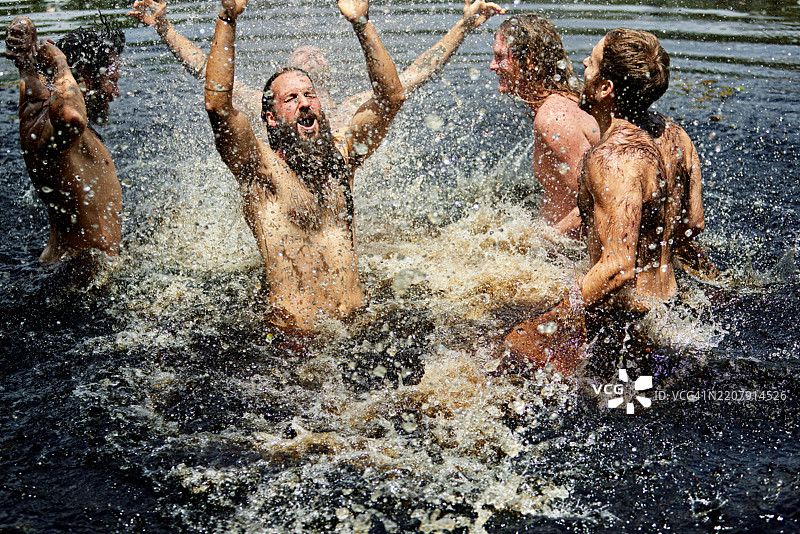 兴奋的男人们在春季湖水中欢快地跳跃图片素材