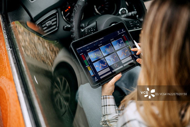 女人坐在车里查看交易图表。图片素材