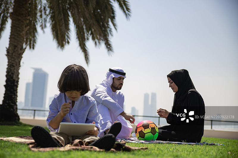 小阿拉伯男孩在公园里使用平板电脑图片素材