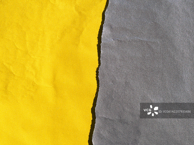一张撕裂的灰色纸和一张明亮的黄色纸,带有阴影。粗糙的纹理。阳光,自然色彩。法国上萨瓦省,埃维昂莱班。图片素材