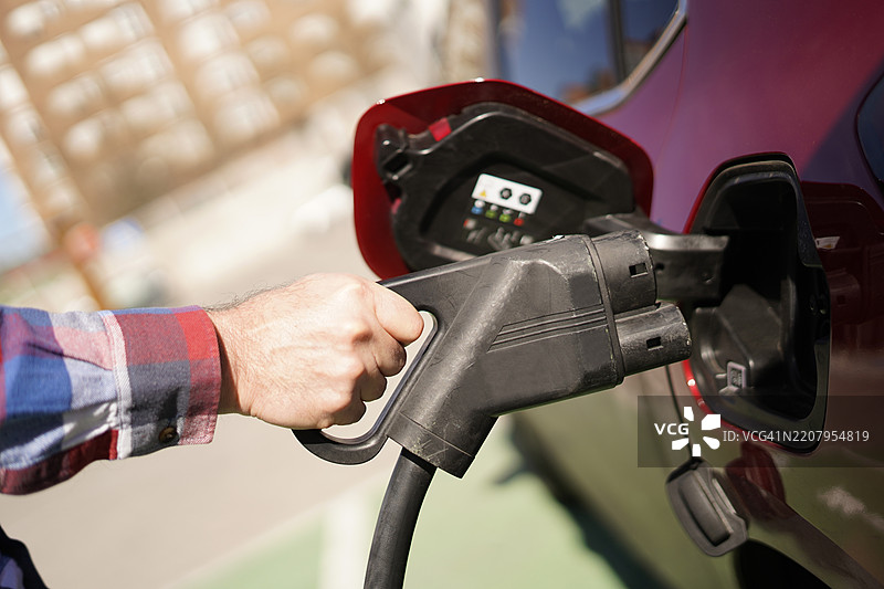一只手臂和手握着一个高功率、快速充电的电池插头图片素材