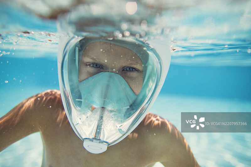 孩子佩戴全脸潜水面罩在水下游泳图片素材