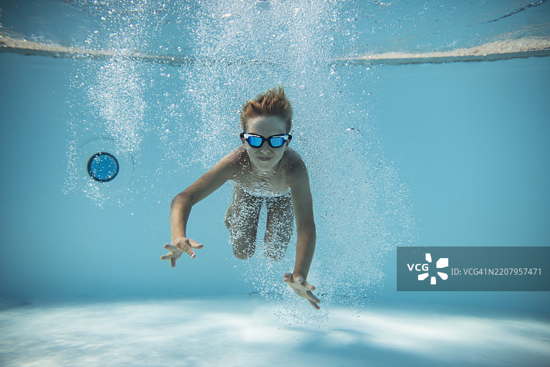 快乐的小男孩在游泳池里跳水的肖像图片素材
